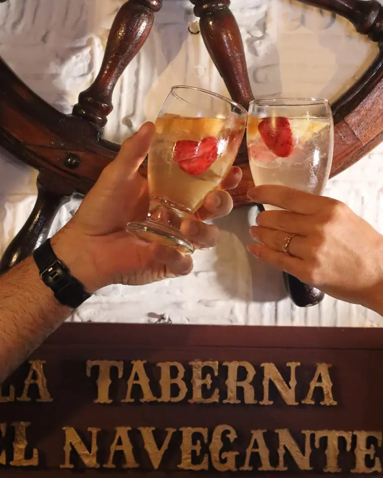 Brindis con sangría blanca frente al timón del local